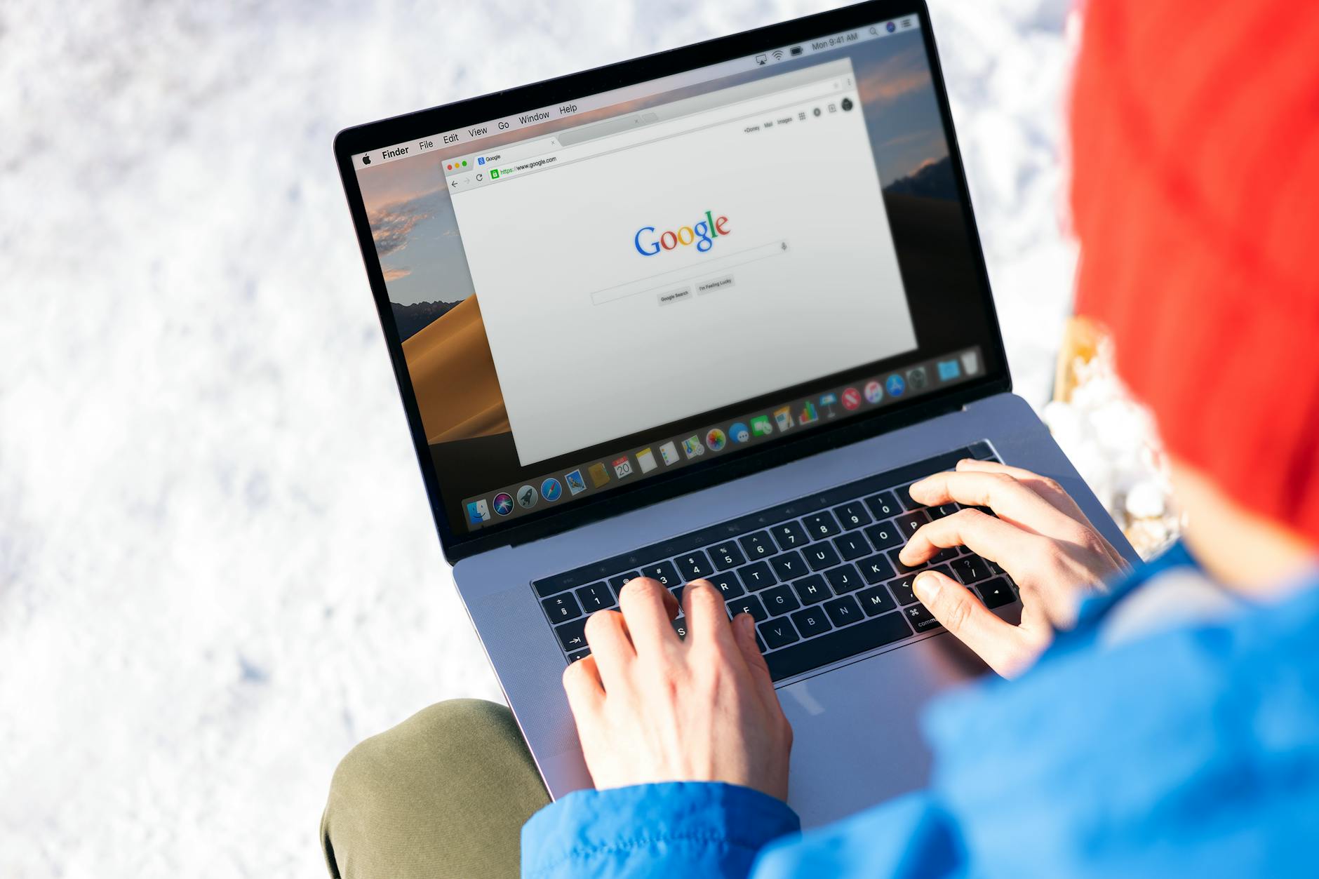 person using macbook pro with google website on screen